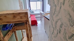 Huone, jossa on sänky, ruokapöytä ja keittiötila.