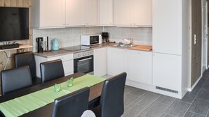 A modern kitchen with white cabinets, a microwave, a coffee maker, and a dining area with a table and chairs.