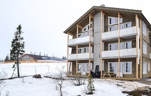 A multi-story building with balconies, a wooden deck, and a snow-covered ground. - Beautiful apartment in Trysil (Trysil)