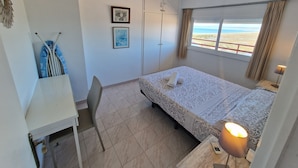 Un dormitorio con cama, escritorio, silla, ventana con vistas y puerta.