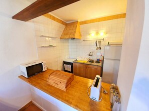A compact kitchen with a microwave, toaster, and wooden storage box on the counter. - APARTMENT PALS BEACH-3 (Pals)