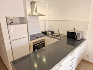 Een moderne keuken met een roestvrijstalen afzuigkap, een inbouwoven, een magnetron en een spoelbak.