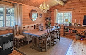 A cozy cabin interior with a wooden dining table, chairs, a chandelier, a fireplace, and a bookshelf. - Cozy home in Noresund with house a panoramic view (Noresund)