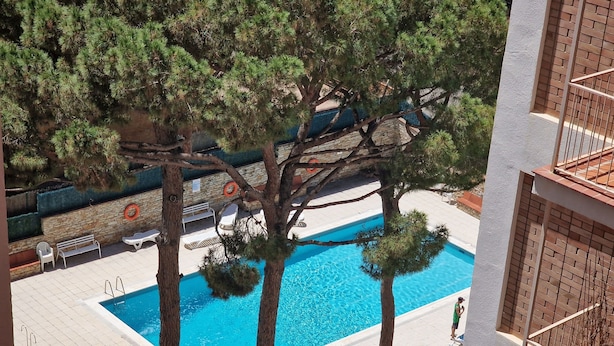 A swimming pool with lounge chairs and a stone wall. - APARTMENT PALS BEACH-6 (Pals)