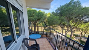 A balcony with a table and chairs, a view of trees, and a railing. - APARTMENT PALS BEACH-6 (Pals)
