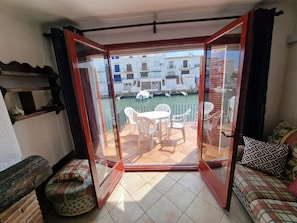 Une pièce dotée d’une porte-fenêtre coulissante donnant sur un balcon avec vue sur des immeubles et un canal.