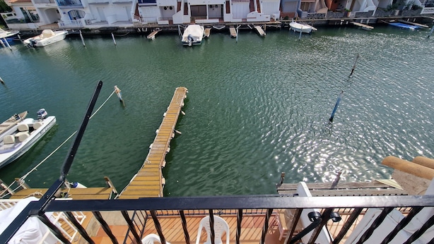 A marina with boats docked, a wooden pier, and a row of buildings with balconies.