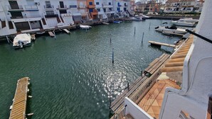 A marina with boats docked, a wooden pier, and buildings with balconies and windows.