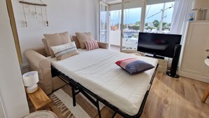 Ein Schlafzimmer mit Bett, Fernseher, Meerblick und einem Balkon mit Stühlen.
