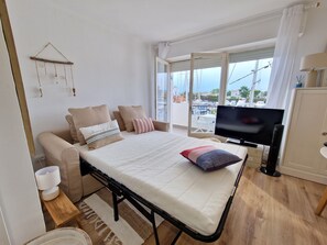 Ein Schlafzimmer mit Bett, Fernseher, Meerblick und einem Balkon mit Stühlen.