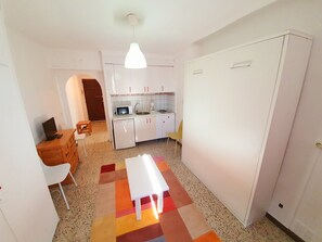 Ein kompakter Wohnbereich mit Küchenzeile, Essplatz und Kleiderschrank.