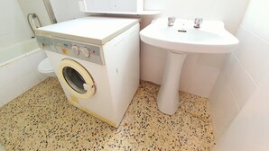 Ein kleiner Waschraum mit Waschmaschine, Spüle und Toilette.
