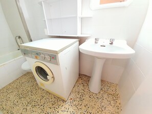 Ein kleiner Waschraum mit Waschmaschine, Spüle und Toilette.
