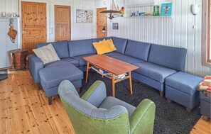 Een gezellige woonkamer met een blauwe modulaire bank, een houten salontafel en een groene fauteuil.