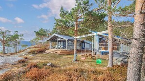Une cabane dotée d’une terrasse, d’un espace extérieur couvert avec des sièges, et offrant une vue sur le paysage environnant.