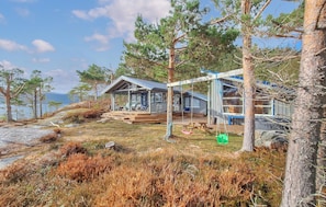 Une cabane dotée d’une terrasse, d’un espace extérieur couvert avec des sièges, et offrant une vue sur le paysage environnant.