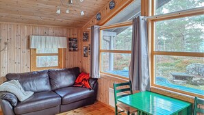 L’intérieur d’un chalet en bois, avec un canapé en cuir, une table verte et une chaise.