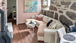 Un salon avec un canapé, une petite table ronde et un mur en pierre.