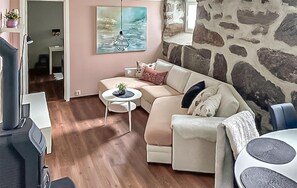 Una sala de estar con un sofá, una mesita redonda y una pared de piedra.
