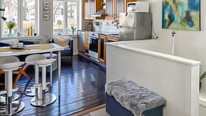 Une cuisine moderne avec des meubles en bois, un réfrigérateur blanc et un coin repas comprenant une table et des chaises.