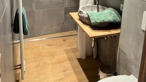 Une salle de bain moderne avec une douche, un meuble-lavabo en bois et un miroir.