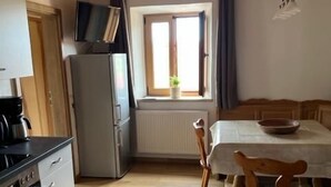 Une cuisine équipée d’une cuisinière, d’un réfrigérateur et d’une table à manger avec des chaises.