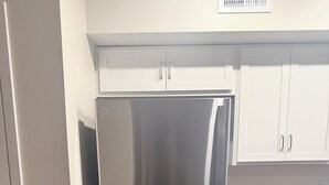 Un réfrigérateur en acier inoxydable dans une cuisine avec des armoires blanches et un comptoir en granit.
