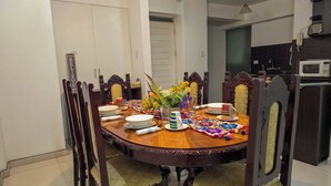 A dining area with a round wooden table, chairs, and a flower centerpiece. - Upscale 3BR Apt in Cusco,Gateway to Machu Picchu , Best Area (Cusco)