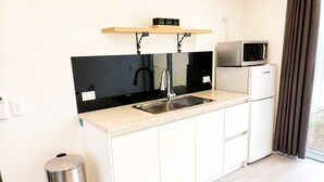 A compact kitchen with a sink, a microwave, and a small refrigerator. - Modern Gound Floor Studio (Cromwell)