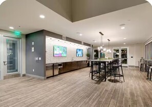 A modern kitchen with a bar area, wooden flooring, and recessed lighting.