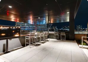 Eine Dachterrasse mit Sitzgelegenheiten und Blick auf die beleuchtete Stadt.