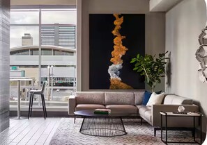 En moderne stue med sofa, sofabord og et stort abstrakt maleri på væggen.