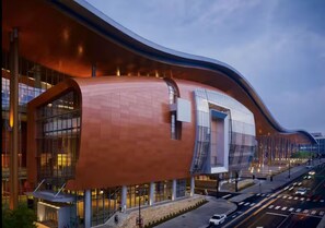 A modern building with a curved facade, large windows, and a prominent entrance. - ~NEW~ Downtown Nashville! Walk to Broadway + FREE parking • Balcony • Pool (Nashville)