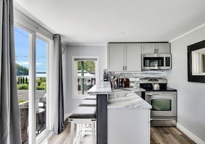 Una cocina con una isla grande, electrodomésticos de acero inoxidable y vistas al exterior.