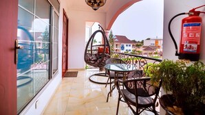 Ein Balkon mit Glastür, einer Hängesessel, einem Tisch mit Stühlen und einem Feuerlöscher.