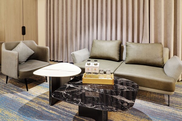A hotel room with a sofa, two armchairs, a small table, and a decorative tray with bottles.