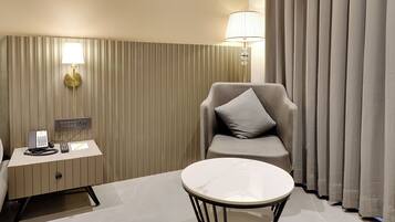 Una habitación de hotel con escritorio, silla y una pequeña mesa redonda.