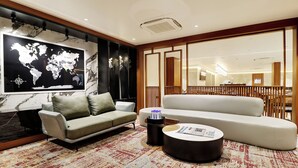 A modern living room with a world map, a grey sofa, a white sofa, a coffee table, and a patterned rug. - Comfort INN Empire Morbi (Morbi)