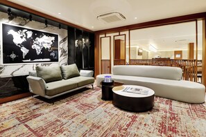 A modern living room with a world map, a grey sofa, a white sofa, a coffee table, and a patterned rug. - Comfort INN Empire Morbi (Morbi)