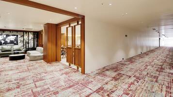Un hall de hotel con un amplio piso alfombrado, una zona de estar con un sofá y sillones, y un mapa mundial colgado en la pared.