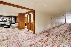 Un hall d’hôtel doté d’une vaste zone recouverte de moquette, d’un espace détente avec un canapé et des fauteuils, et d’une carte du monde accrochée au mur.