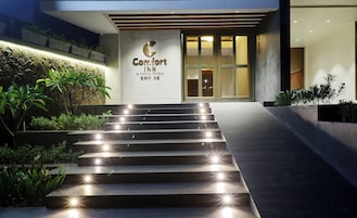 Entrada de un hotel con un cartel que dice 'Comfort Inn by CHOICE HOTELS EMPIRE', un conjunto de escalones que conducen a la entrada y una fachada bien iluminada.