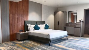 Una habitació d'hotel moderna amb un llit gran, una tauleta de nit, un armari i un mirall.