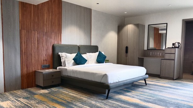 A modern hotel room with a large bed, a nightstand, a wardrobe, and a mirror. - Comfort INN Empire Morbi (Morbi)
