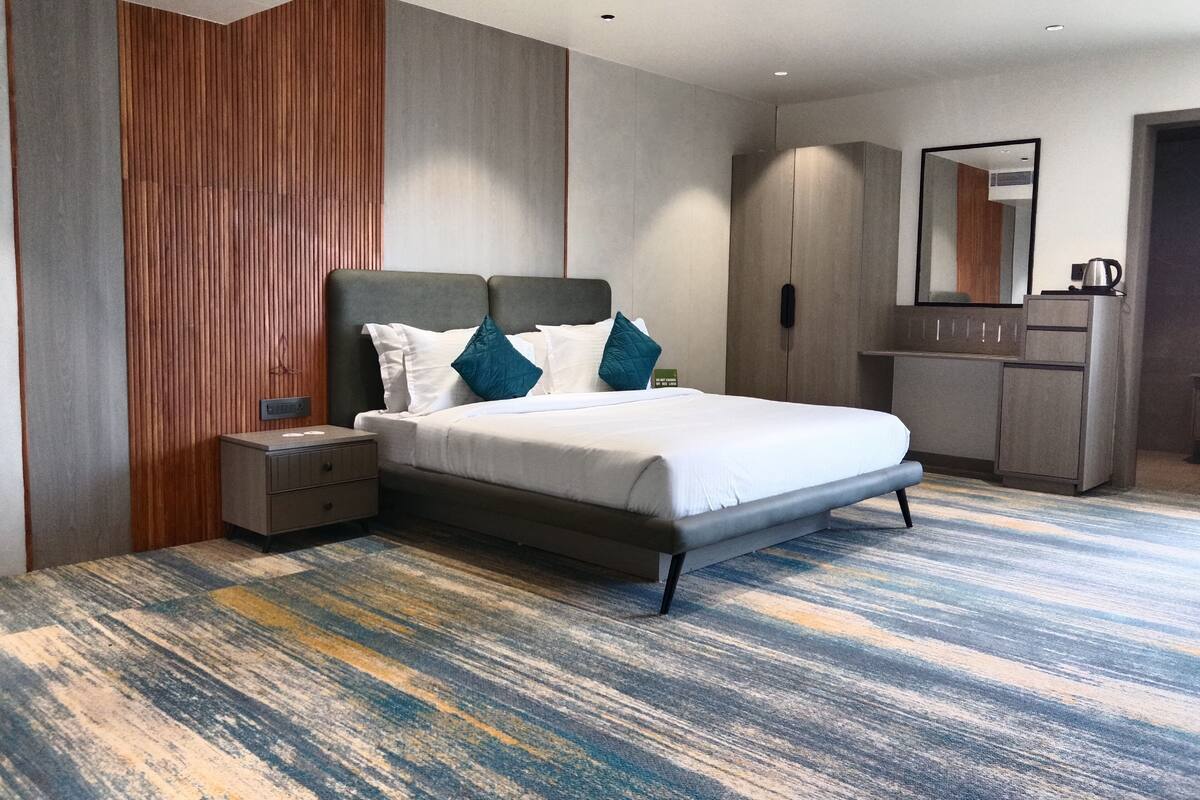 Ein modernes Hotelzimmer mit einem großen Bett, einem Nachttisch, einem Kleiderschrank und einem Spiegel.