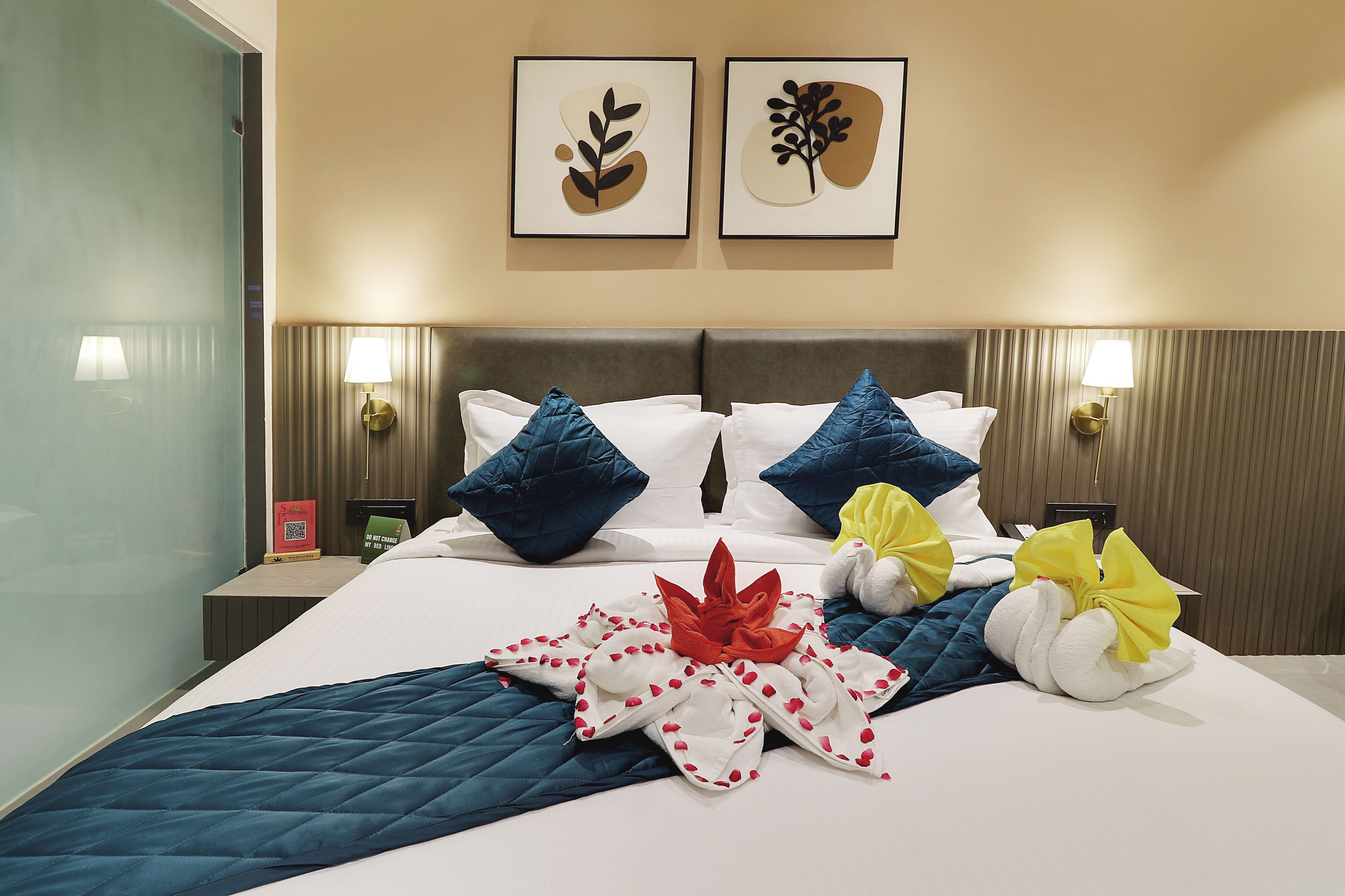 Una habitación de hotel con una cama, almohadas, colcha y cuadros en la pared.