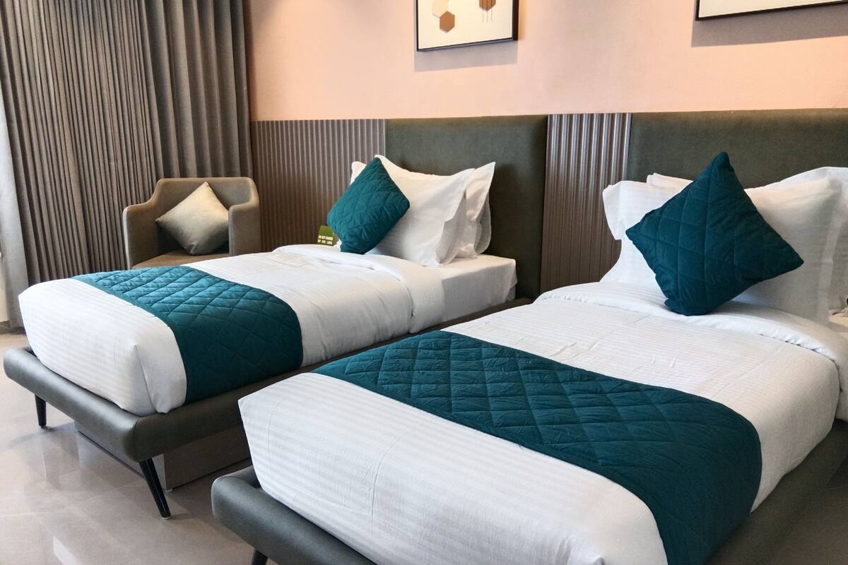 Ein Hotelzimmer mit zwei Betten, einem Sessel und einem Wandbild.