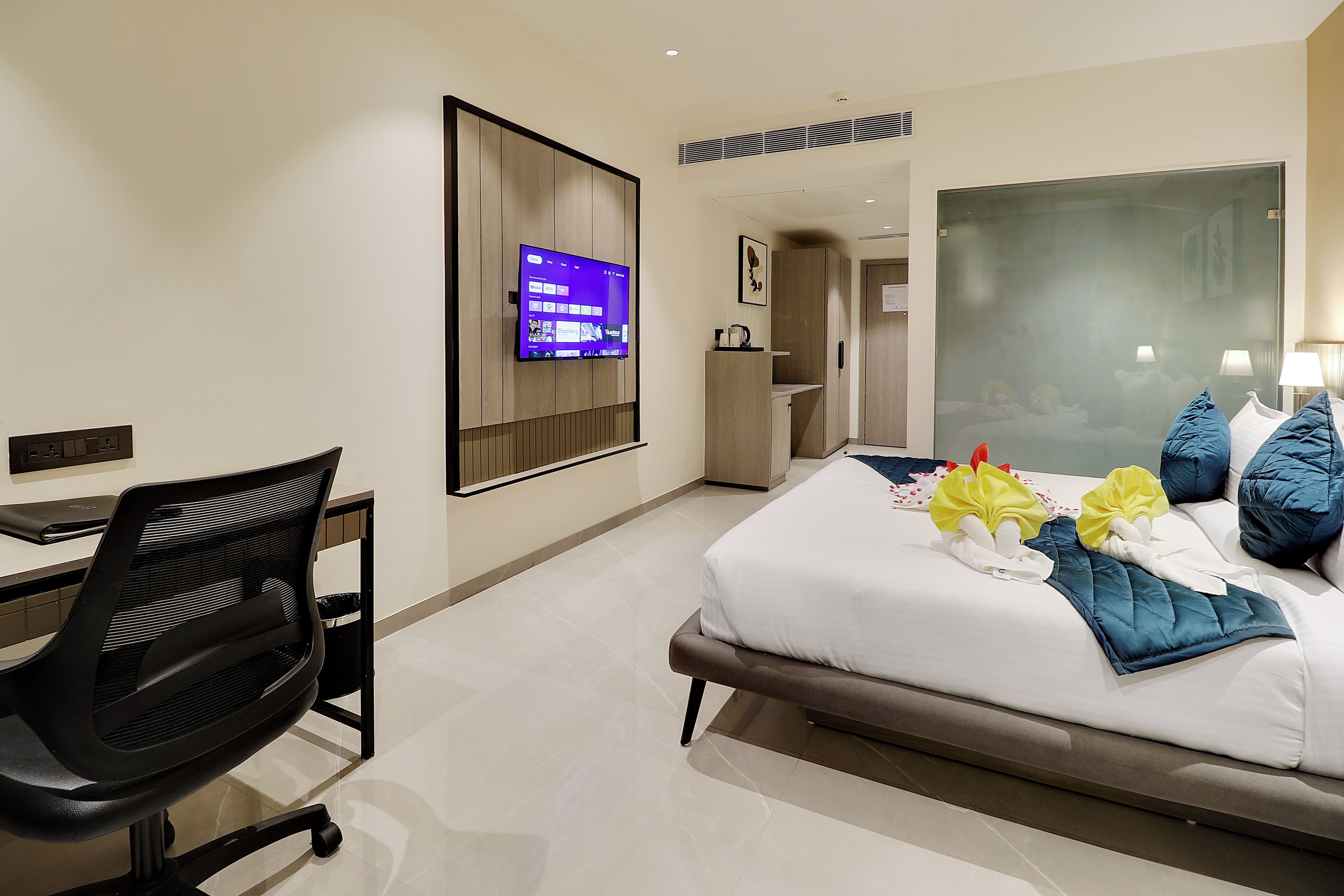 A hotel room with a bed, a desk, a chair, a television, and a bathroom.