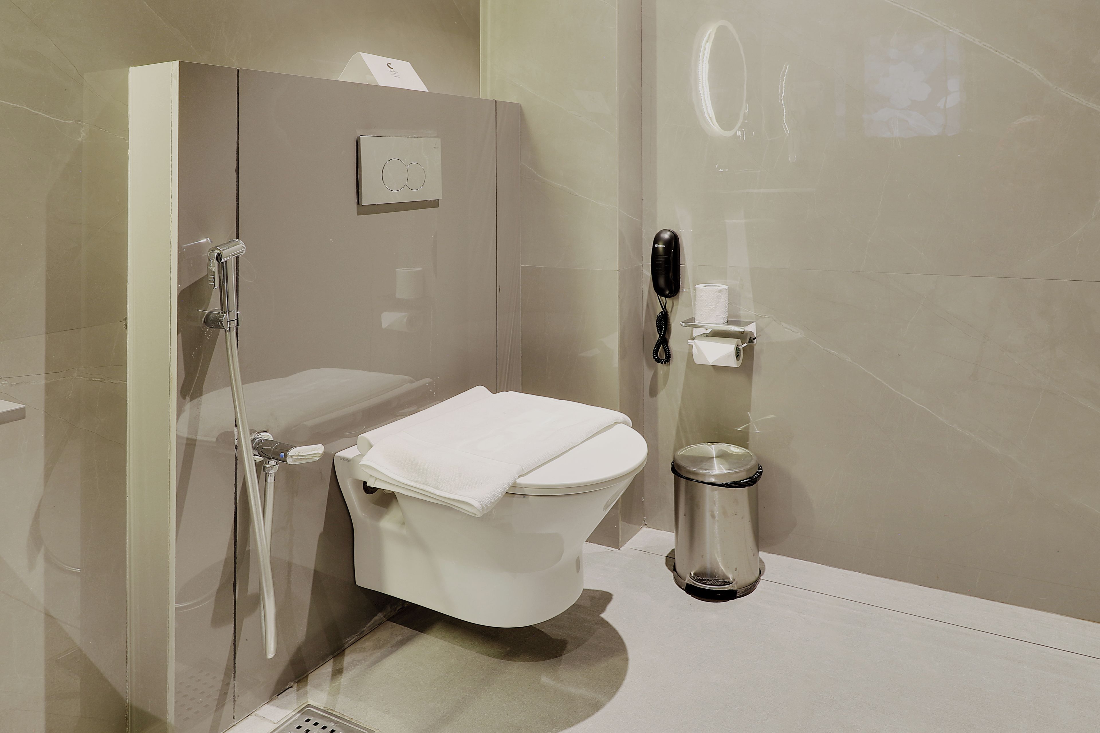 A modern bathroom with a glass-enclosed shower, a toilet, and a trash bin.