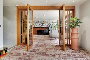 Un hall de hotel con un mostrador de recepción de madera, una zona de estar y una planta grande en maceta.